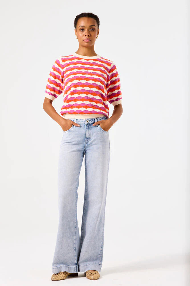 Person wearing a colourful short sleeve striped sweater and light blue jeans on a white background