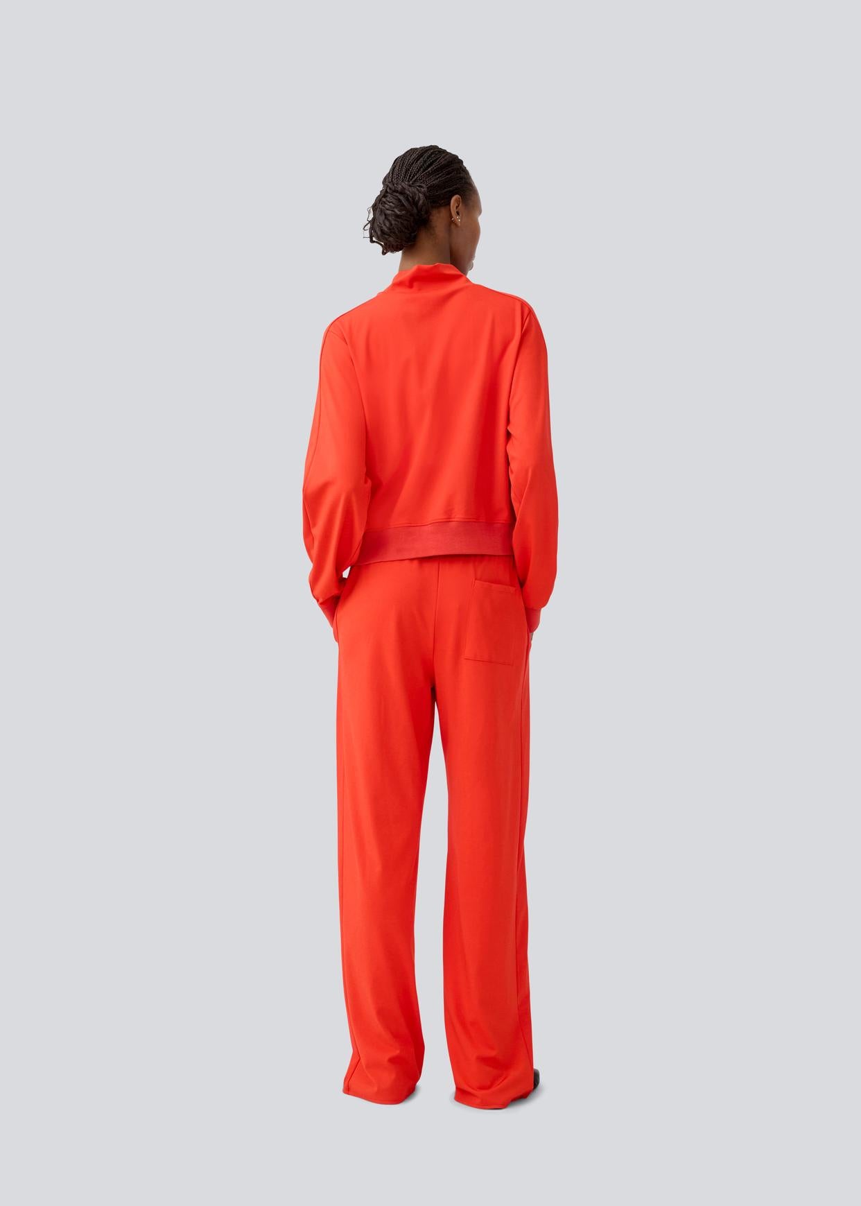Model wearing a bright red tracksuit on a light gray background