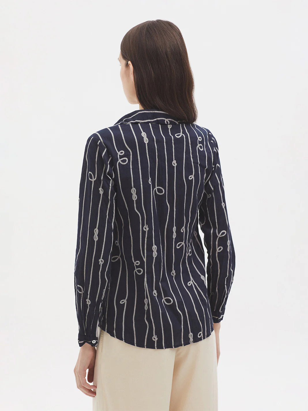 Woman wearing a navy blue patterned shirt on a white background