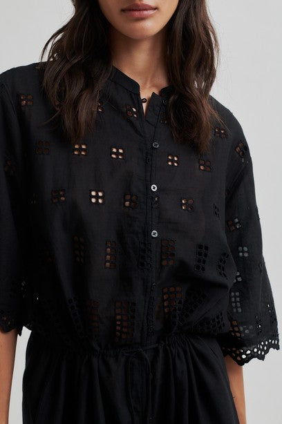 Black dress with intricate cut-out details on a plain background