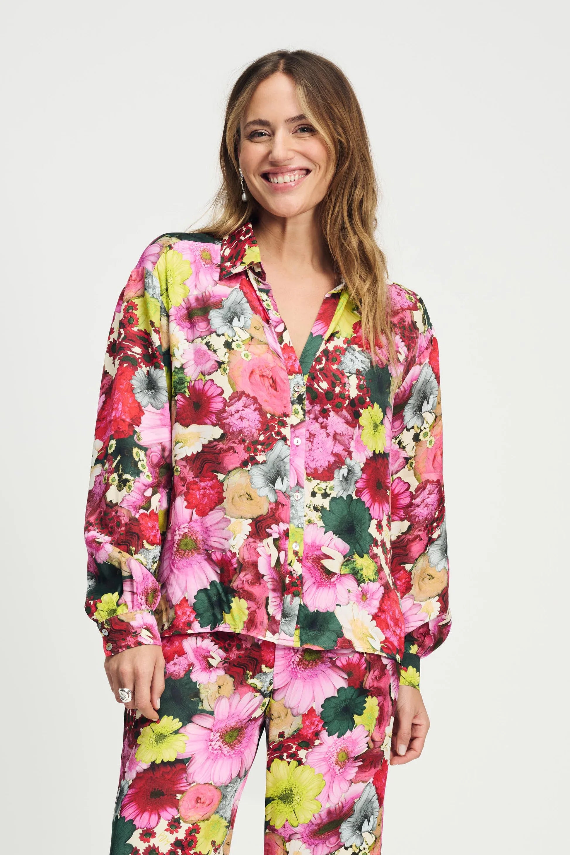 Model wearing a long sleeve bright floral blouse and matching pant on a plain background