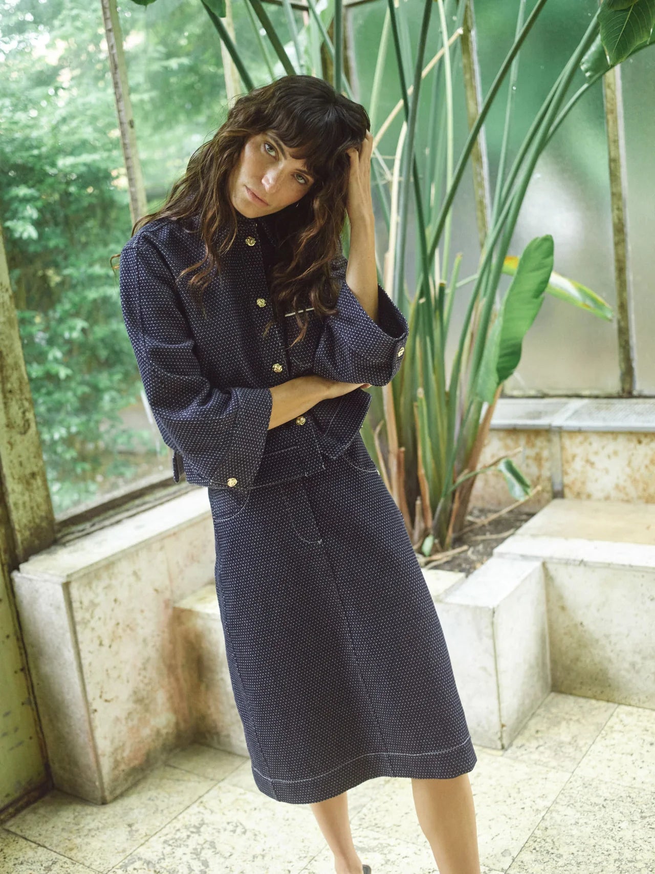 Woman wearing a navy blue outfit with a textured pattern in an indoor setting with plants.