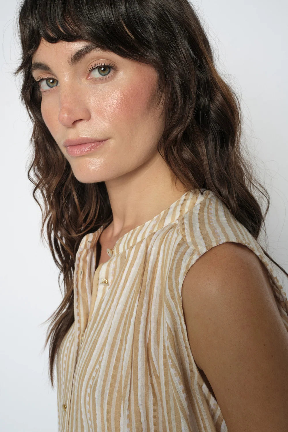 Woman wearing a sleeveless striped top against a plain background