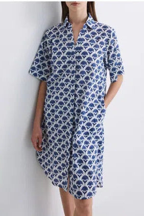 Model wearing a blue and white patterned shirt dress with short sleeves  on a light grey background