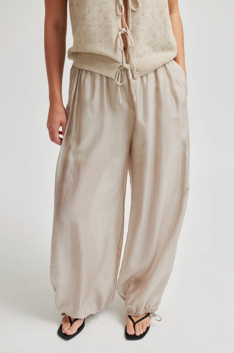 Person wearing beige pants and a matching top on a white background