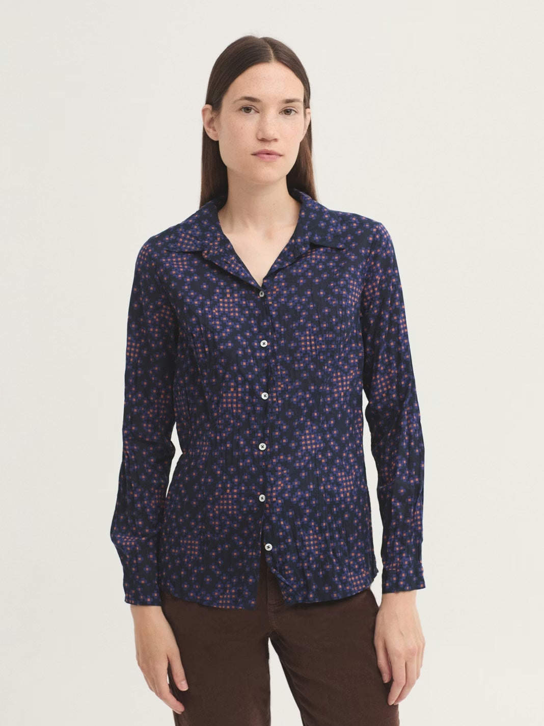 Woman wearing a patterned shirt on a plain background