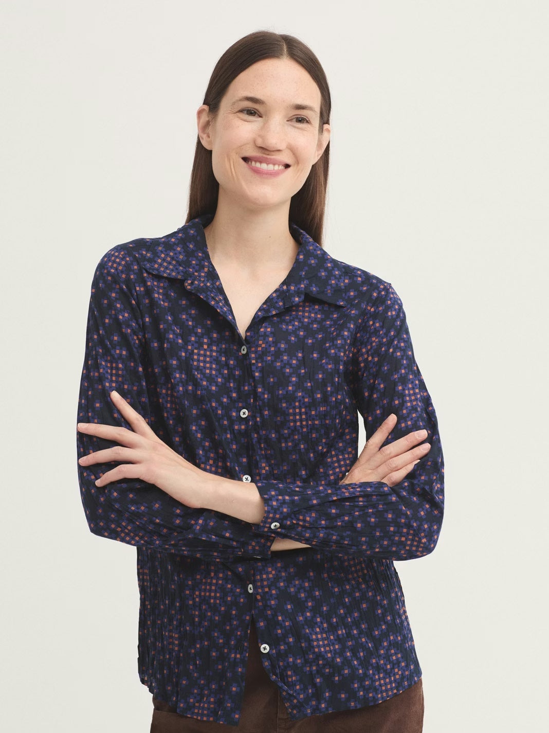 Woman wearing a dark blue patterned shirt on a plain background