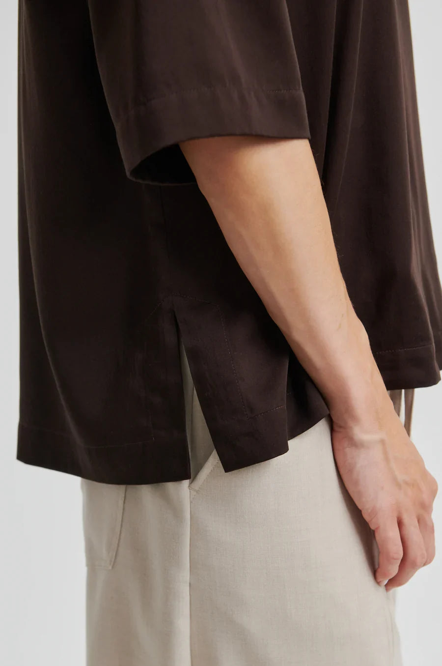 Women wearing a brown oversized shirt and beige pants on a light background