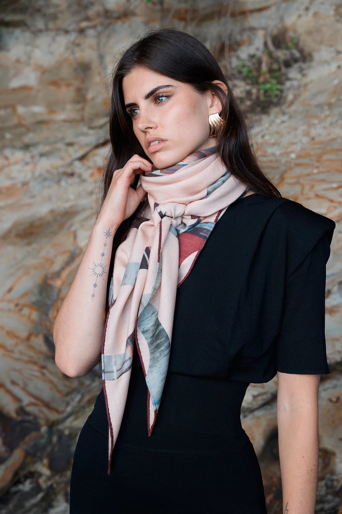 Woman wearing a patterned scarf against a stone wall background