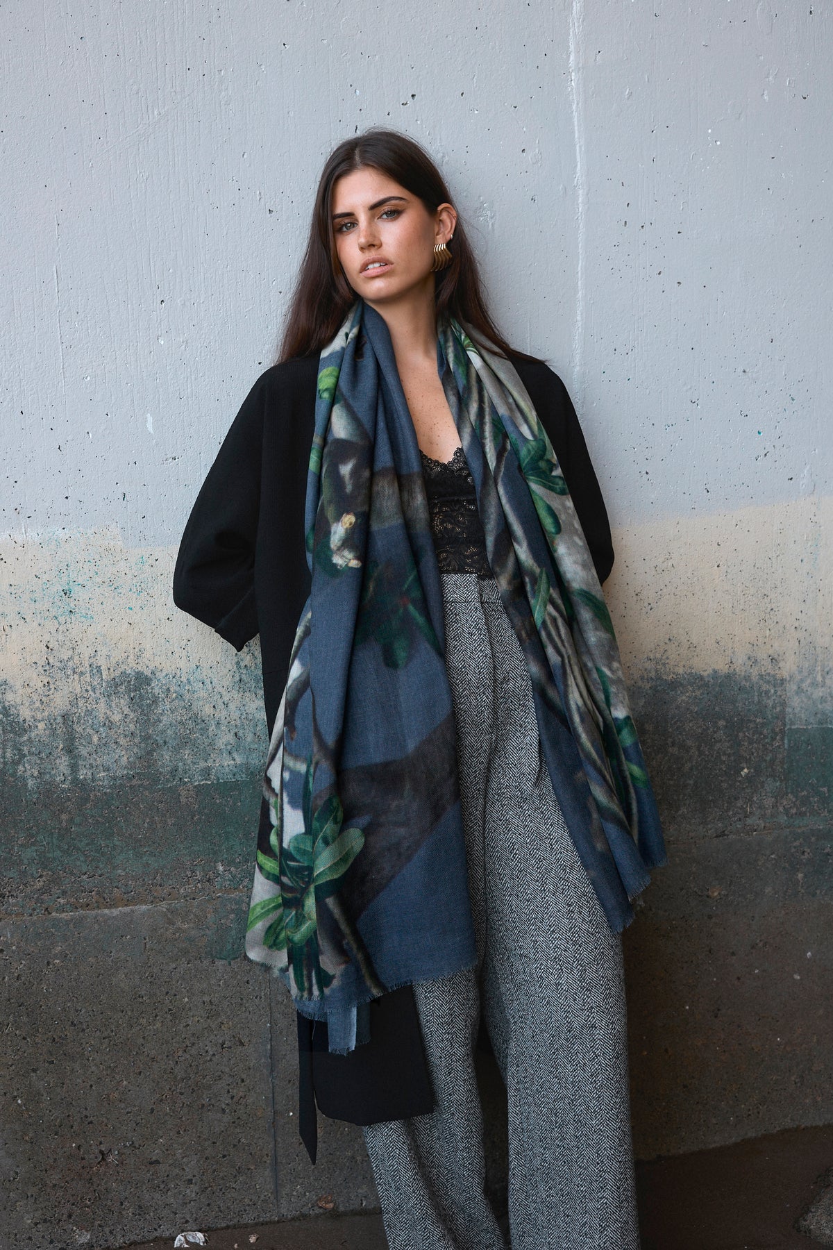 Woman wearing a large scarf against a textured wall