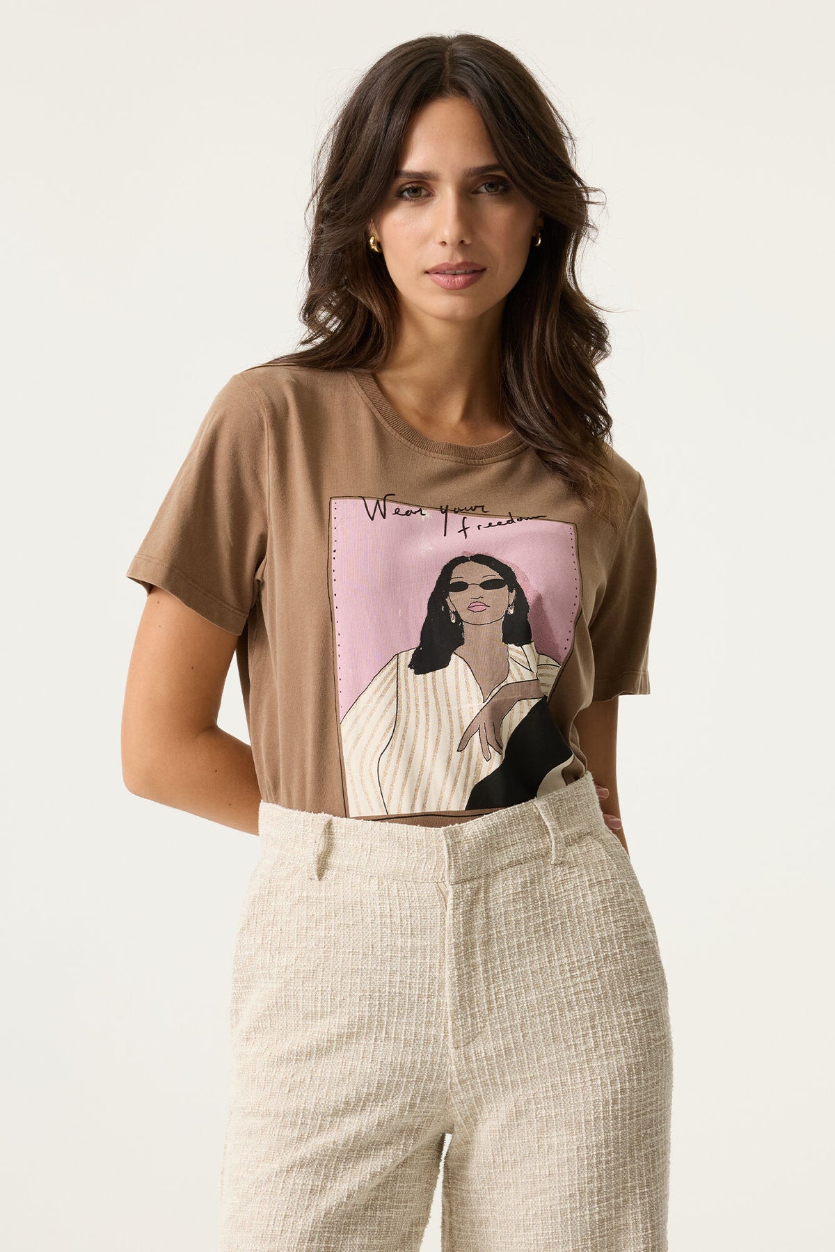 Woman wearing a brown t-shirt with a graphic design on a plain background