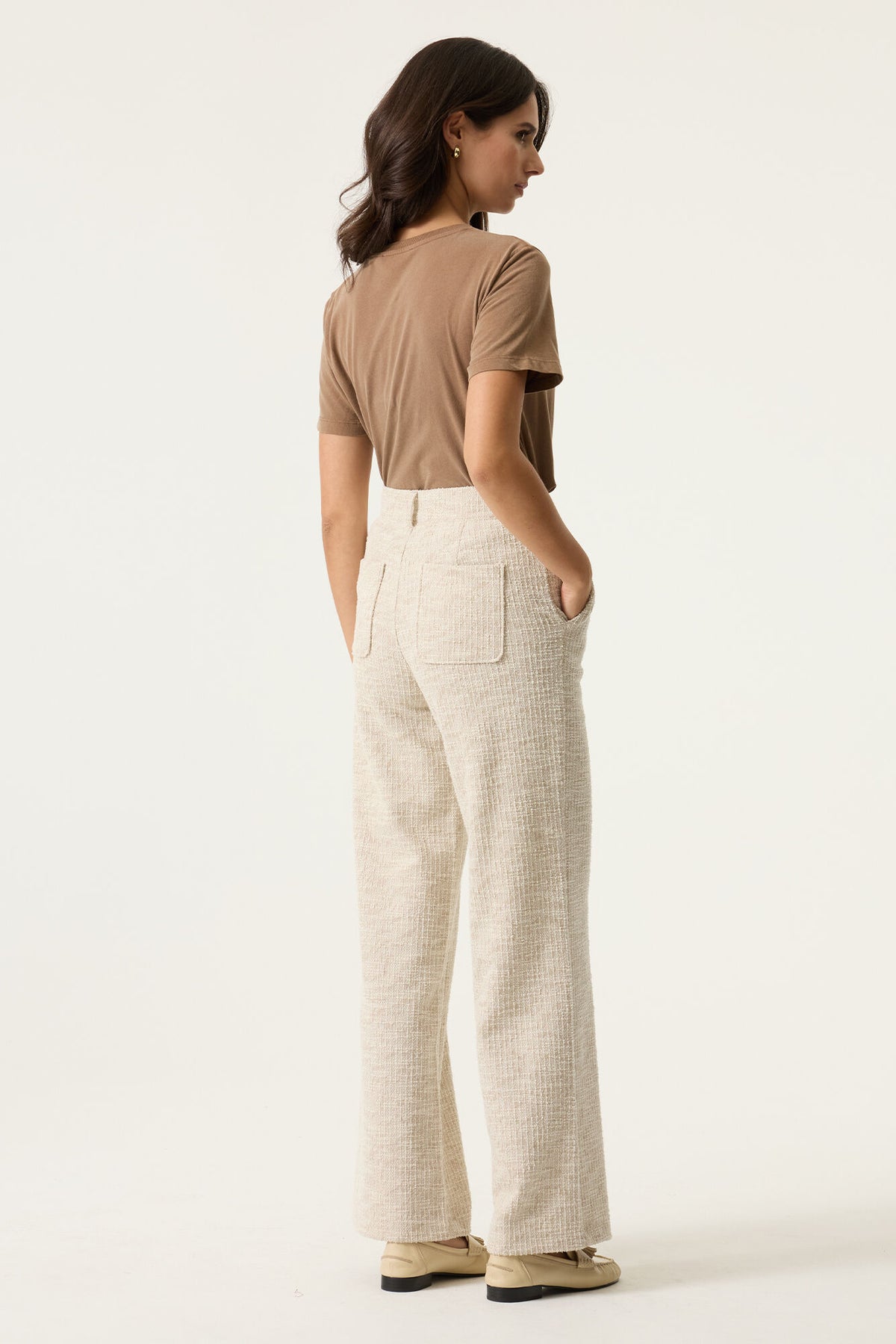 Woman wearing a beige top and light-colored pants on a white background