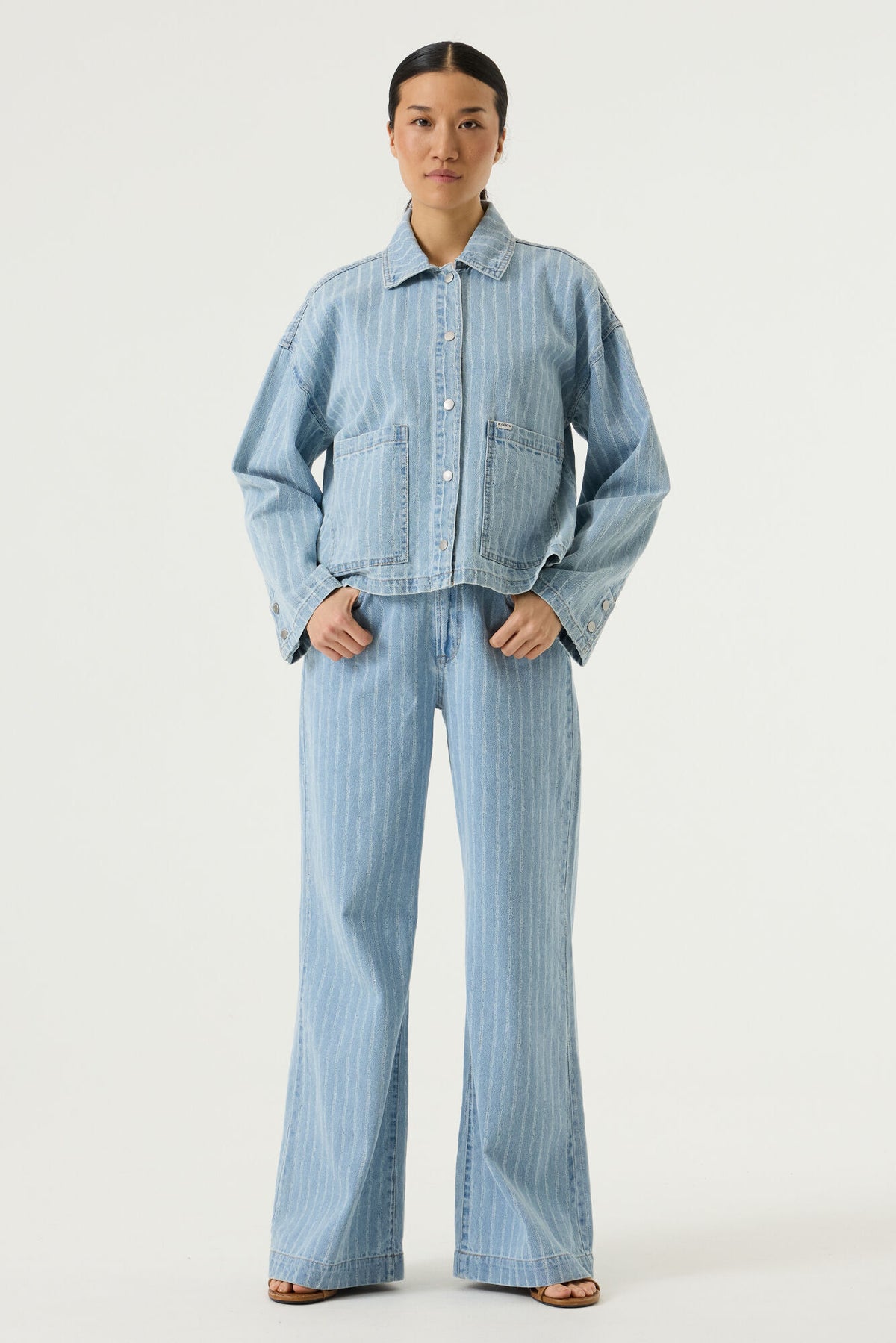 model wearing a blue striped shirt and matching wide leg pants on a white background