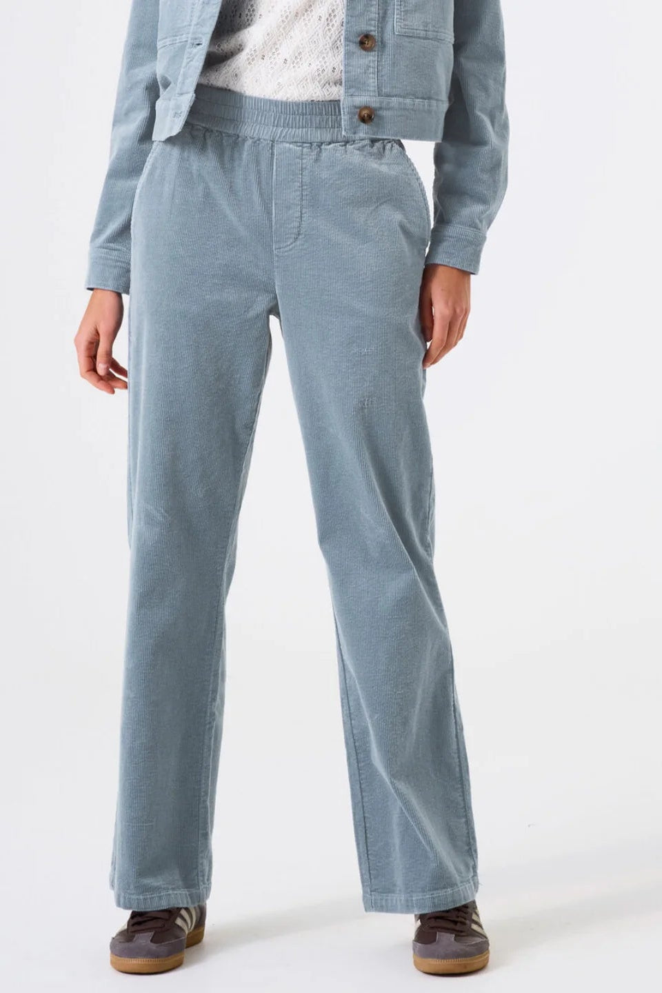 Person wearing a light blue corduroy outfit on a white background
