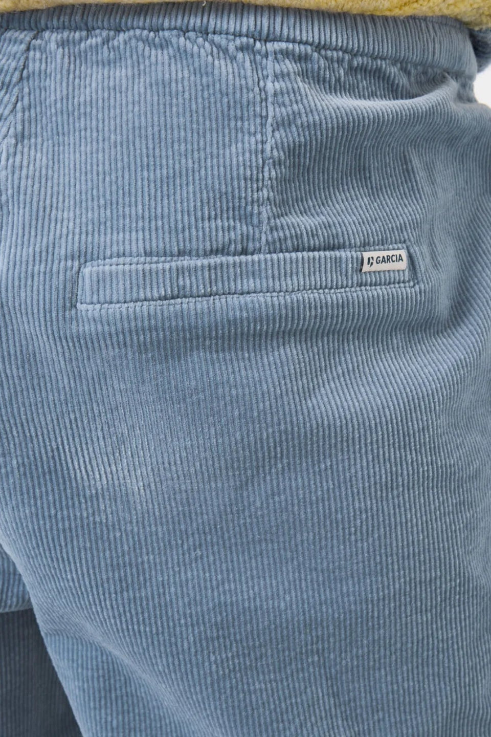 Blue corduroy pants with a brand label on a light gray background
