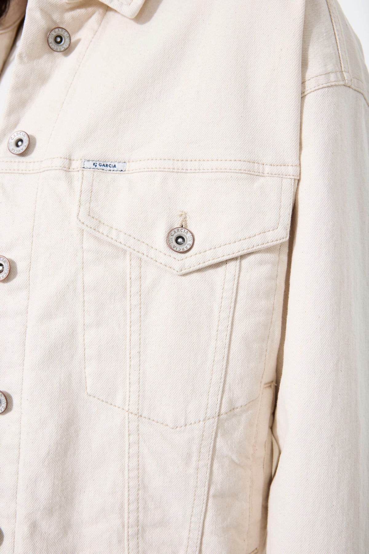 Close-up of a  Ecru denim jacket with button details on a white background