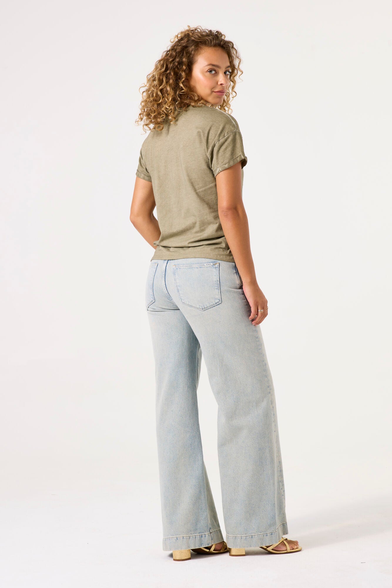Model wearing here comes the sun graphic tee in olive from garcia with denim jeans on a white background. 