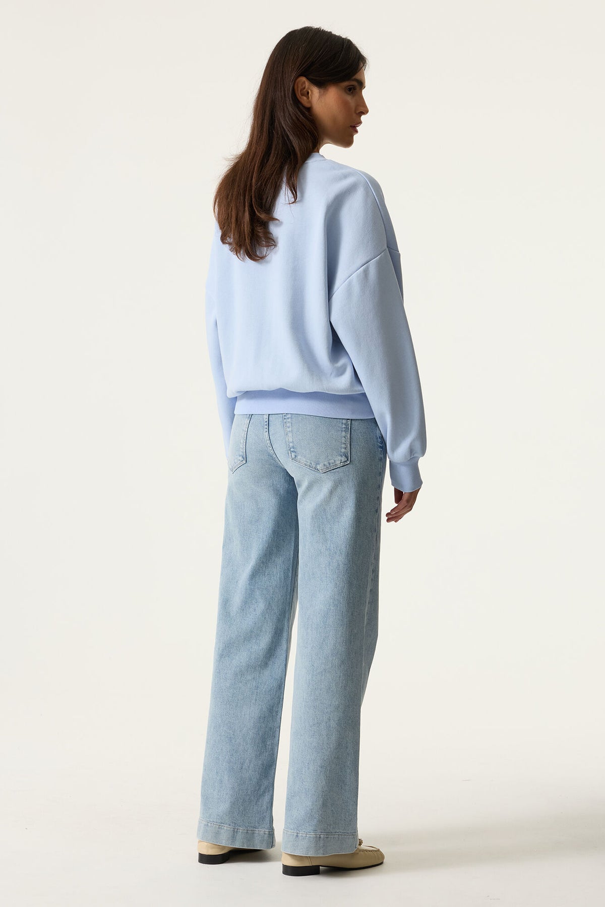 Person wearing a light blue sweater and jeans on a white background