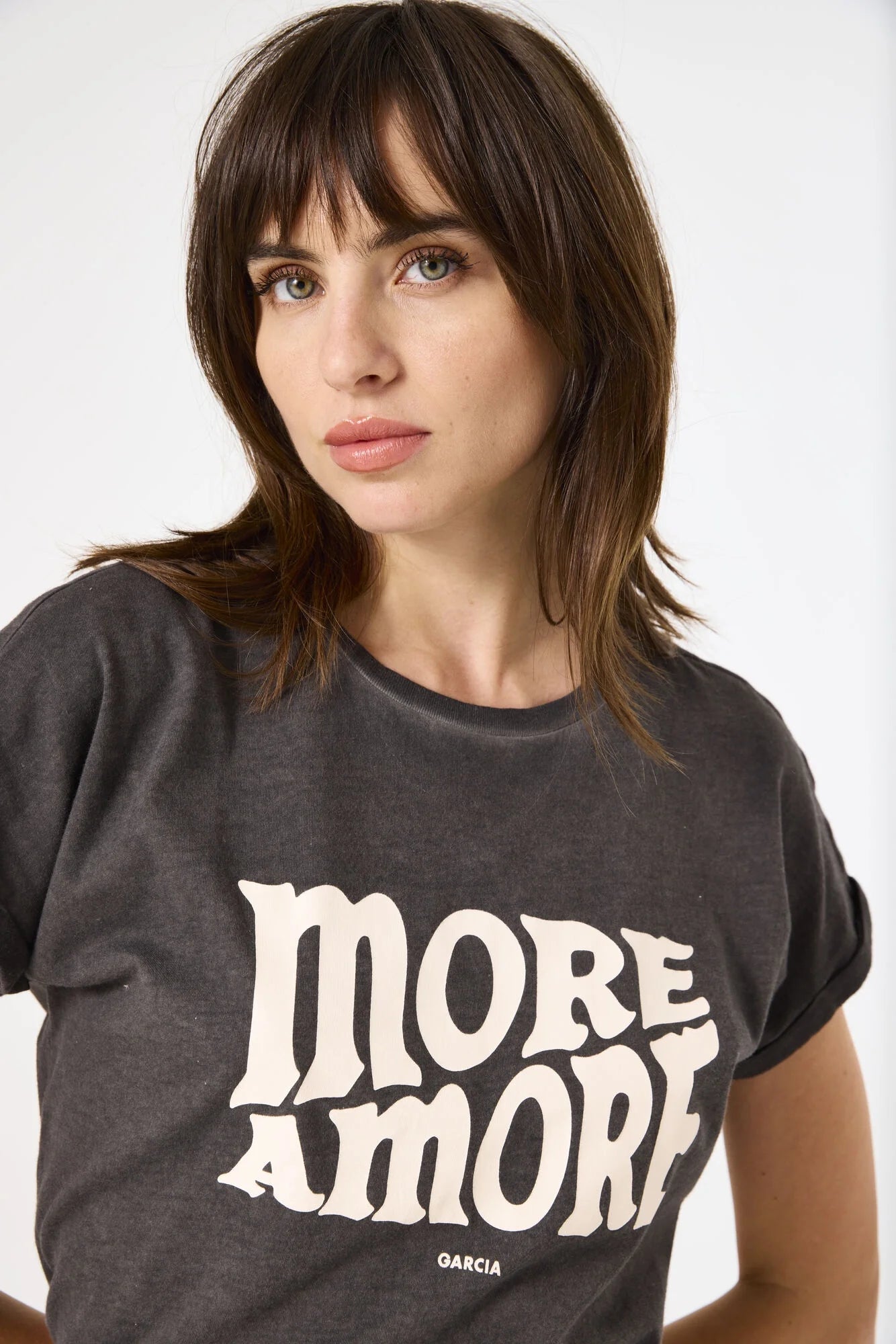 Woman wearing a dark gray t-shirt with 'MORE AMORE GARCIA' text on a white background