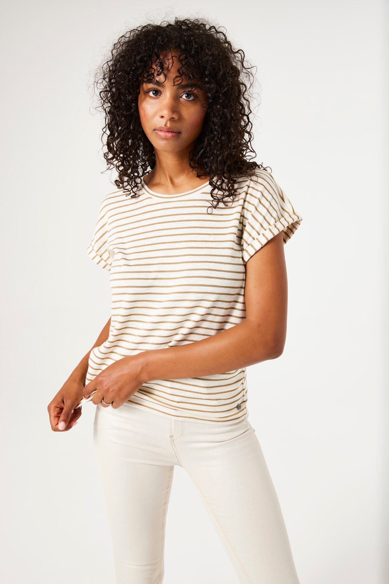 Woman wearing a striped shirt and white pants against a plain background