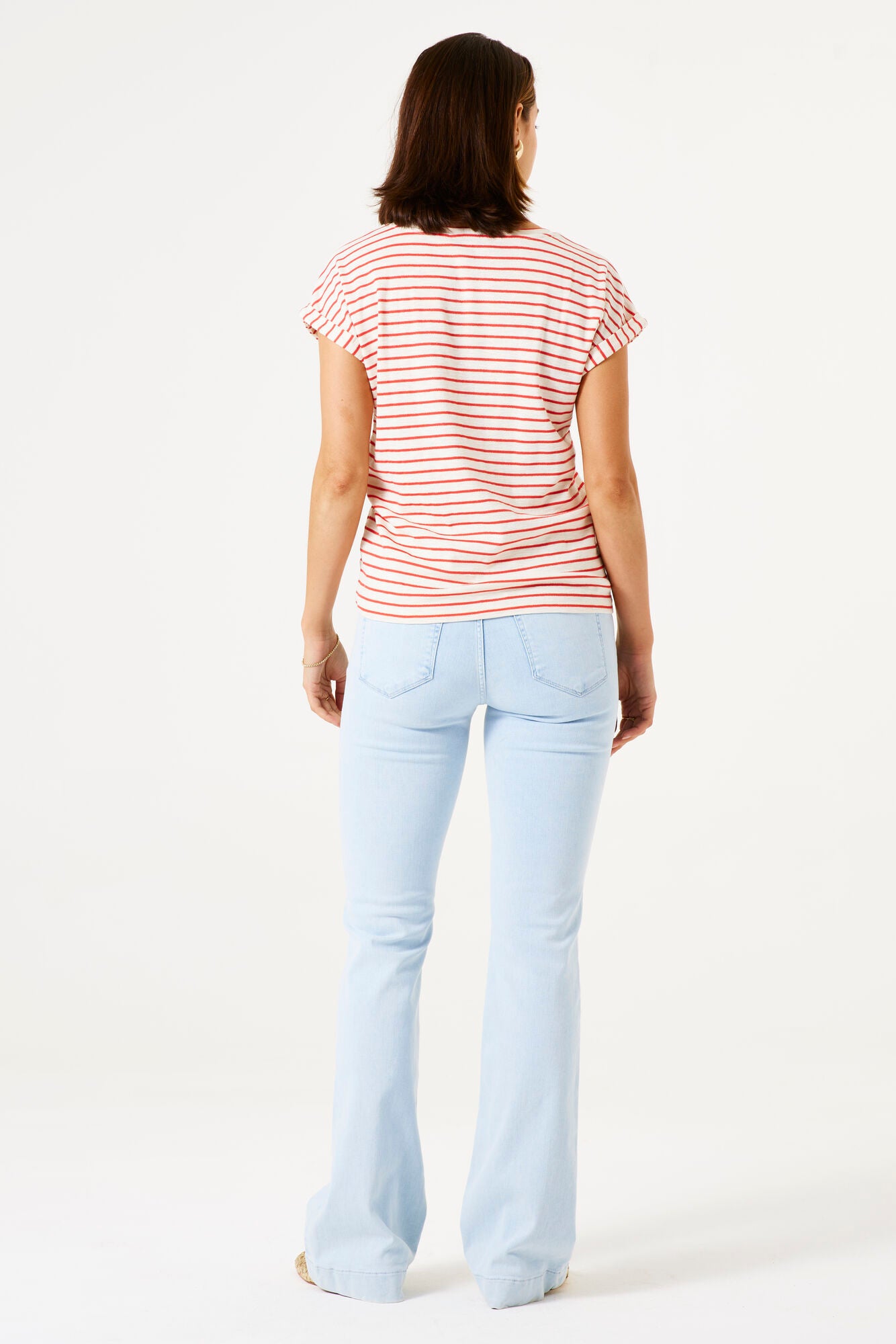 Woman wearing a striped shirt and light blue jeans on a white background