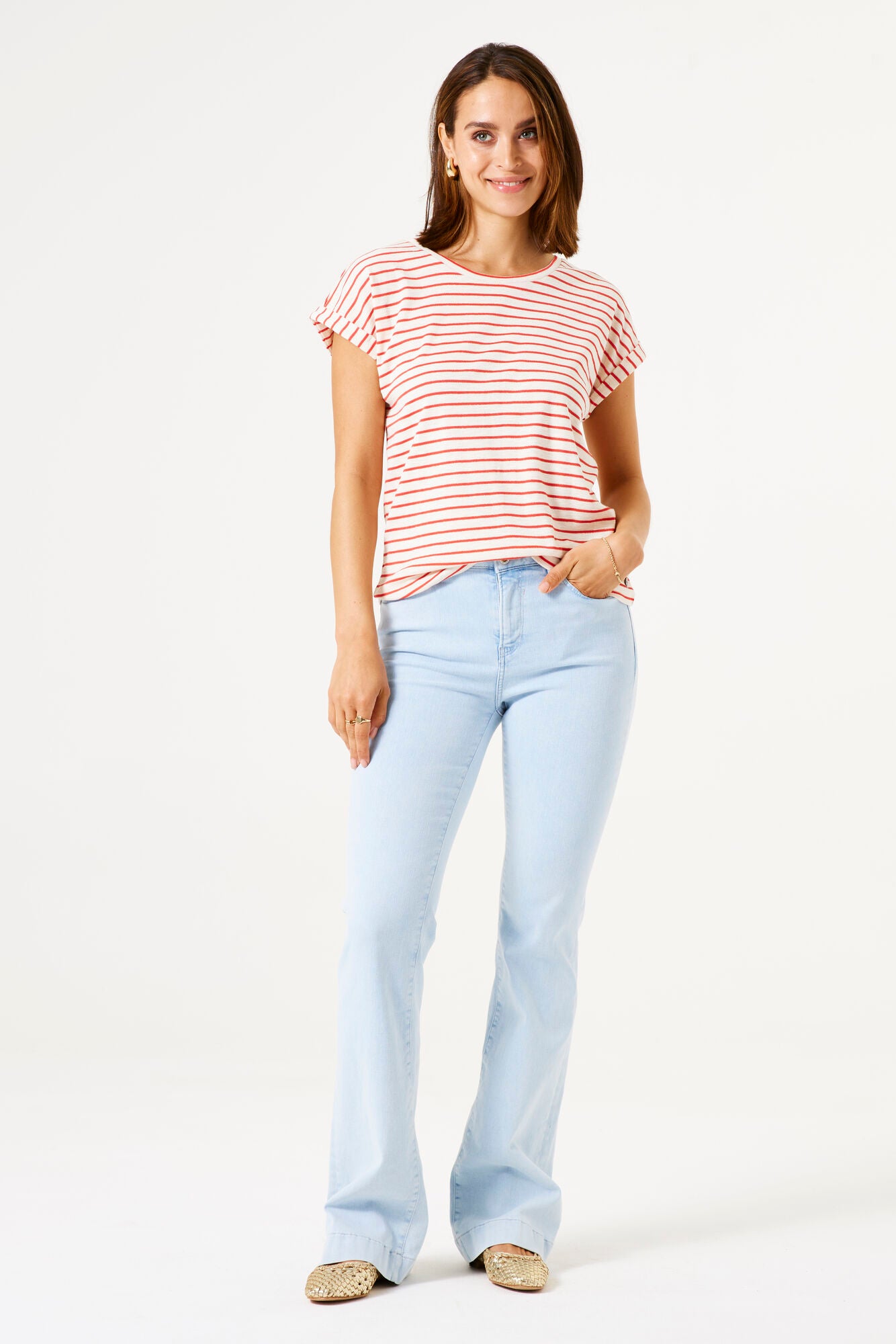 Woman wearing a striped shirt and light blue jeans on a white background