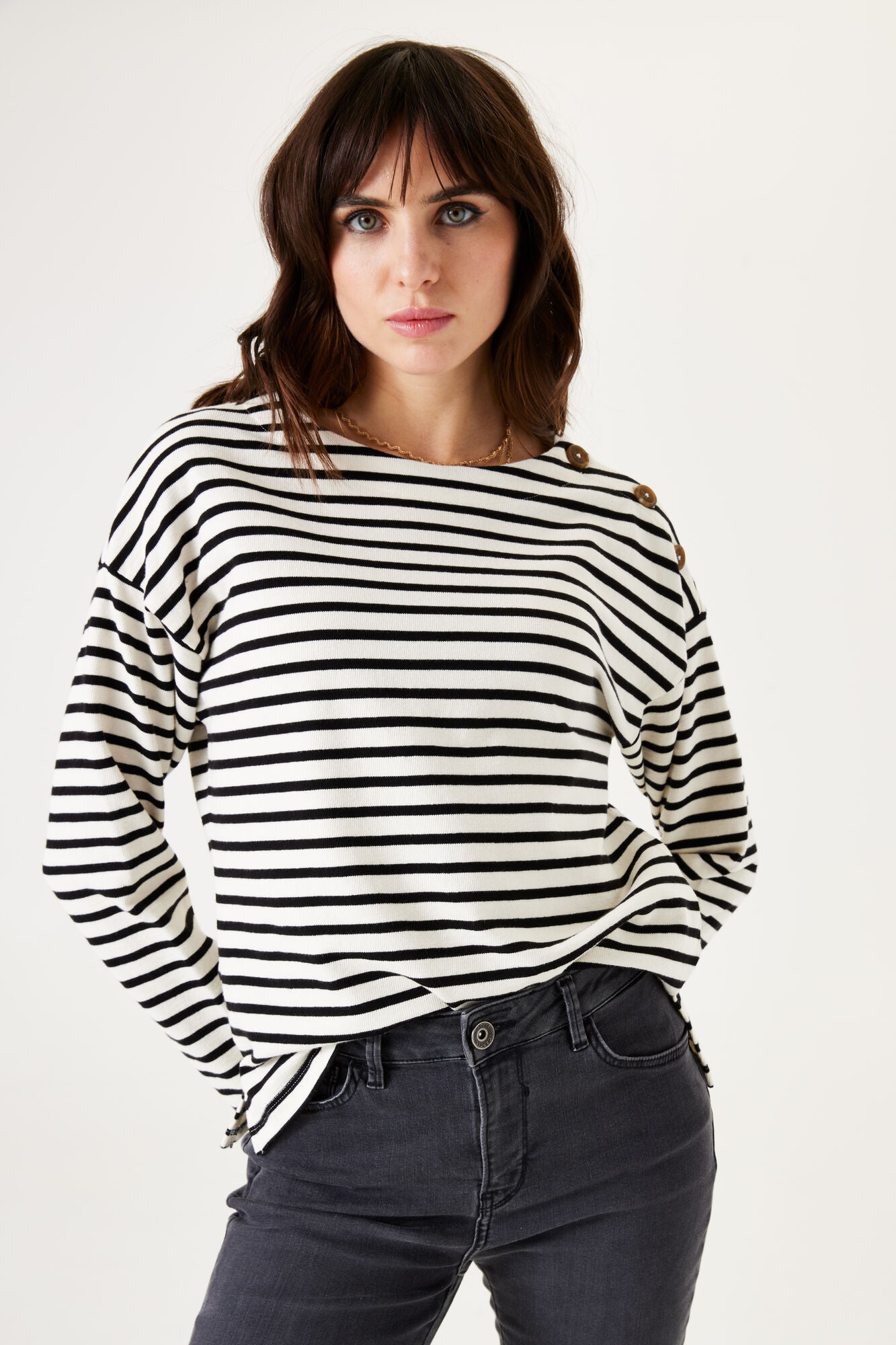 Woman wearing a black and white striped sweater with a plain background