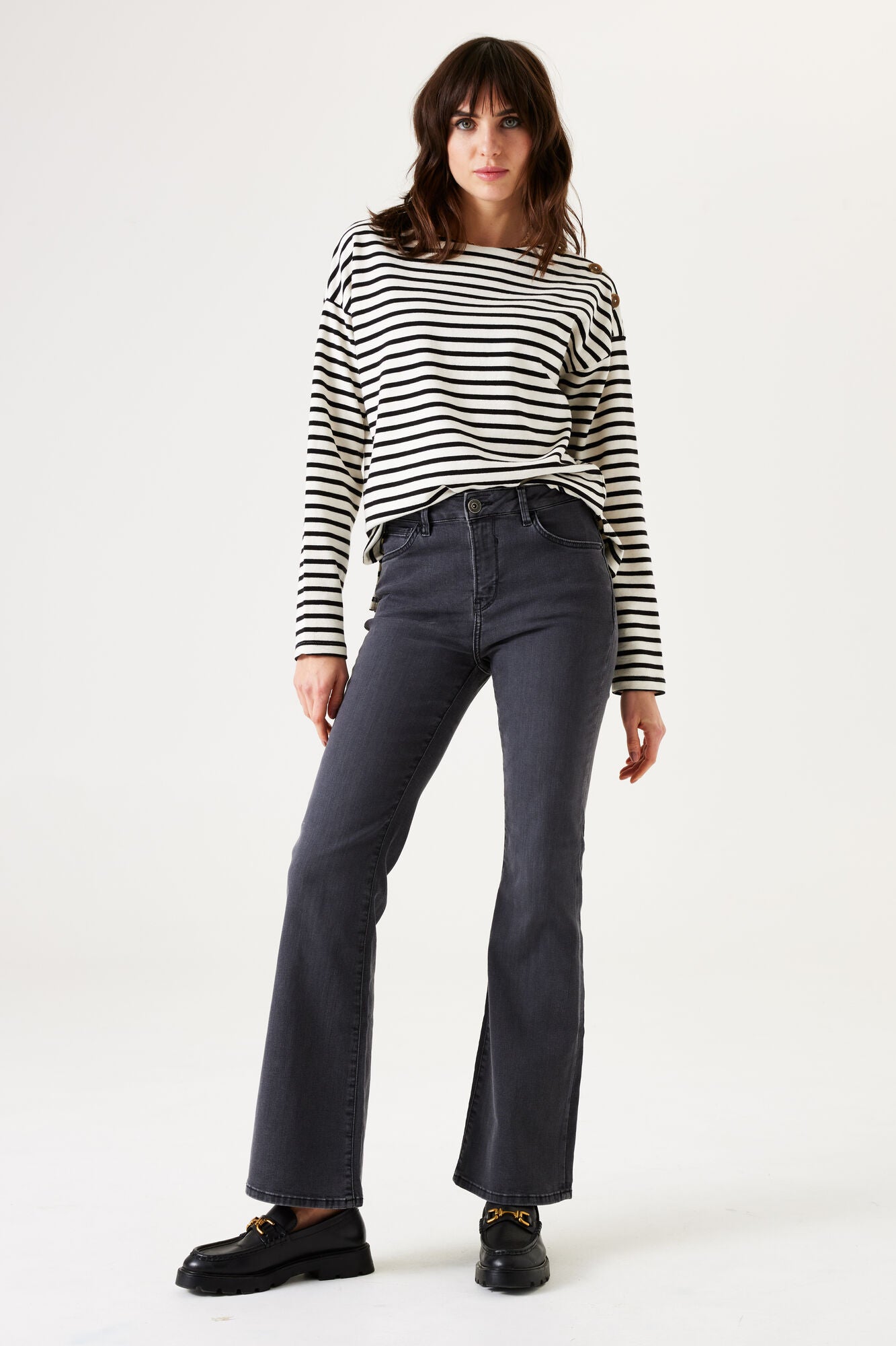 Woman wearing a striped shirt and dark jeans on a white background