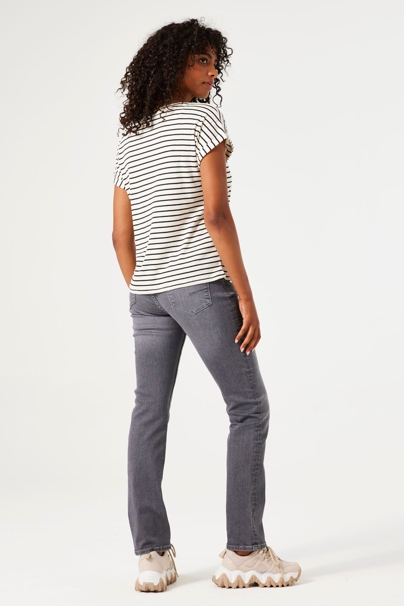 Woman wearing a striped shirt and gray jeans on a white background