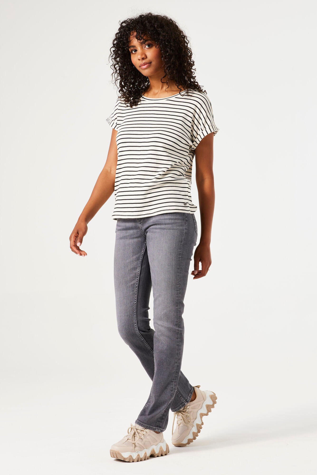 Woman wearing a striped shirt and gray pants on a white background