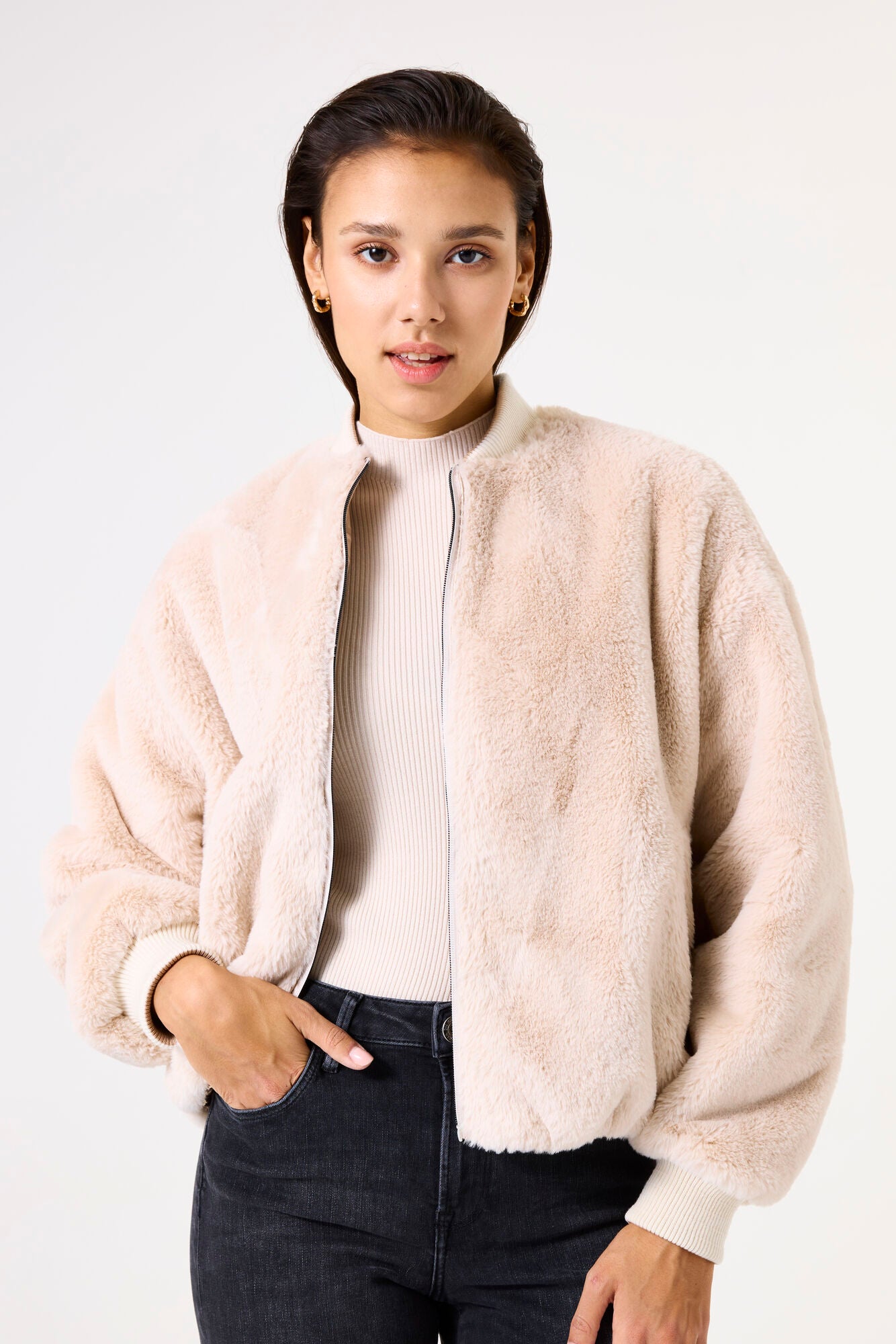 Woman wearing a beige sherpa jacket on a white background
