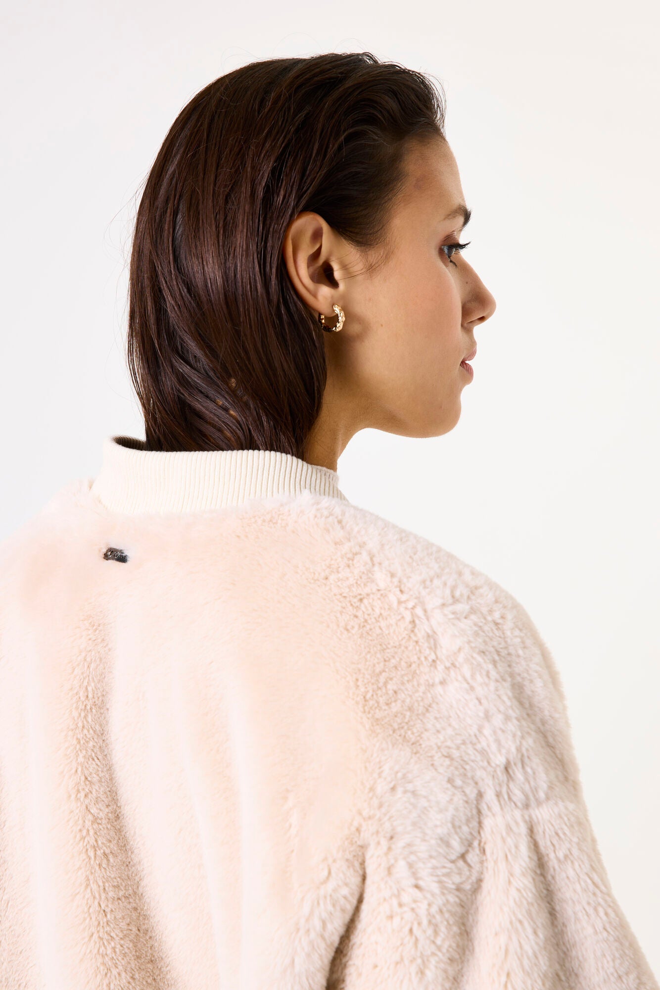 Woman wearing a beige sherpa bomber jacket on a white background