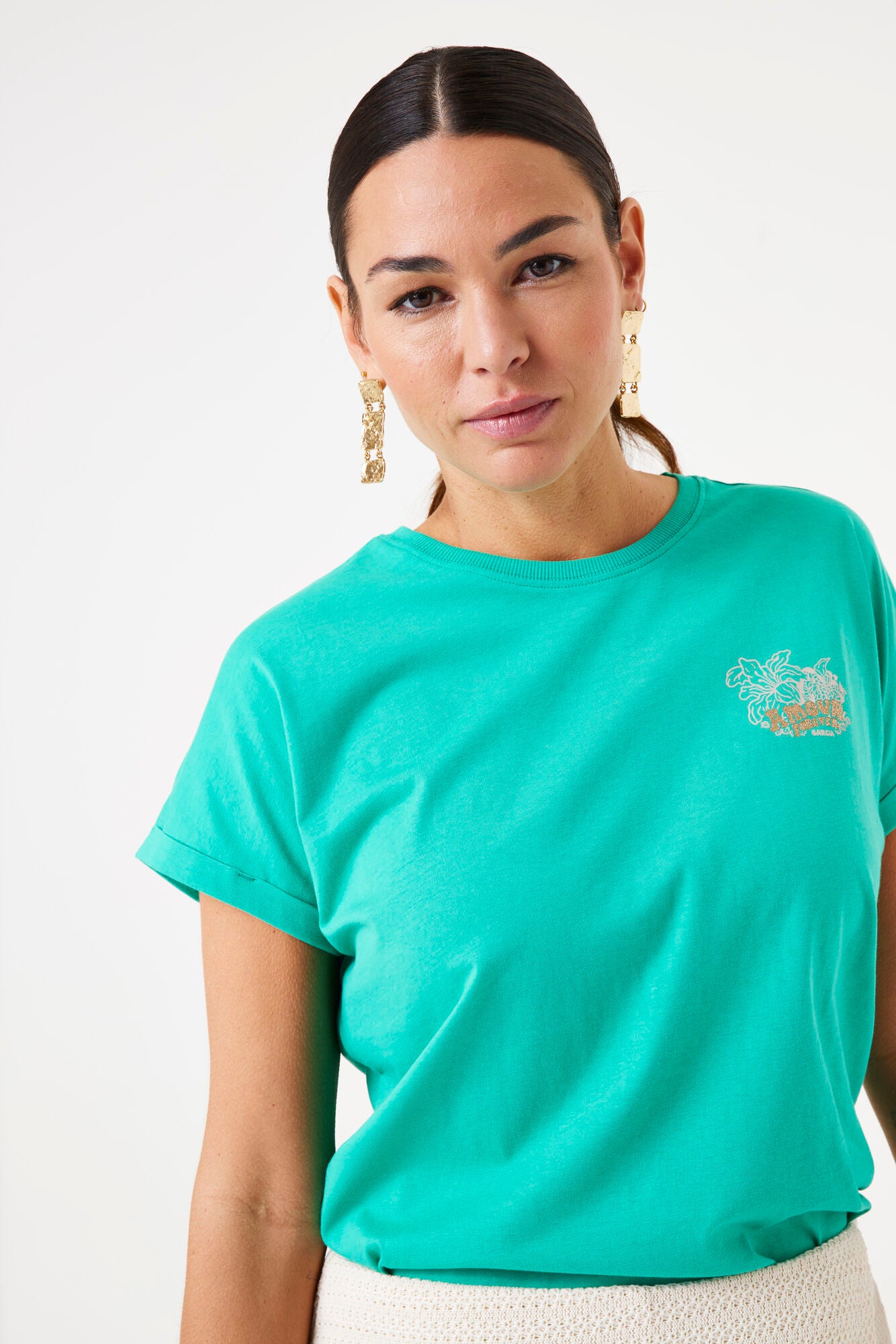 Woman wearing a teal t-shirt with a small graphic on a white background