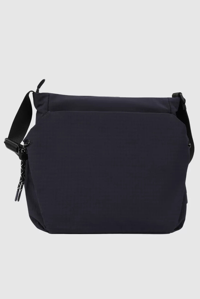 A dark navy blue crossbody bag with a black shoulder strap and zipper pull, shown against a light gray background.