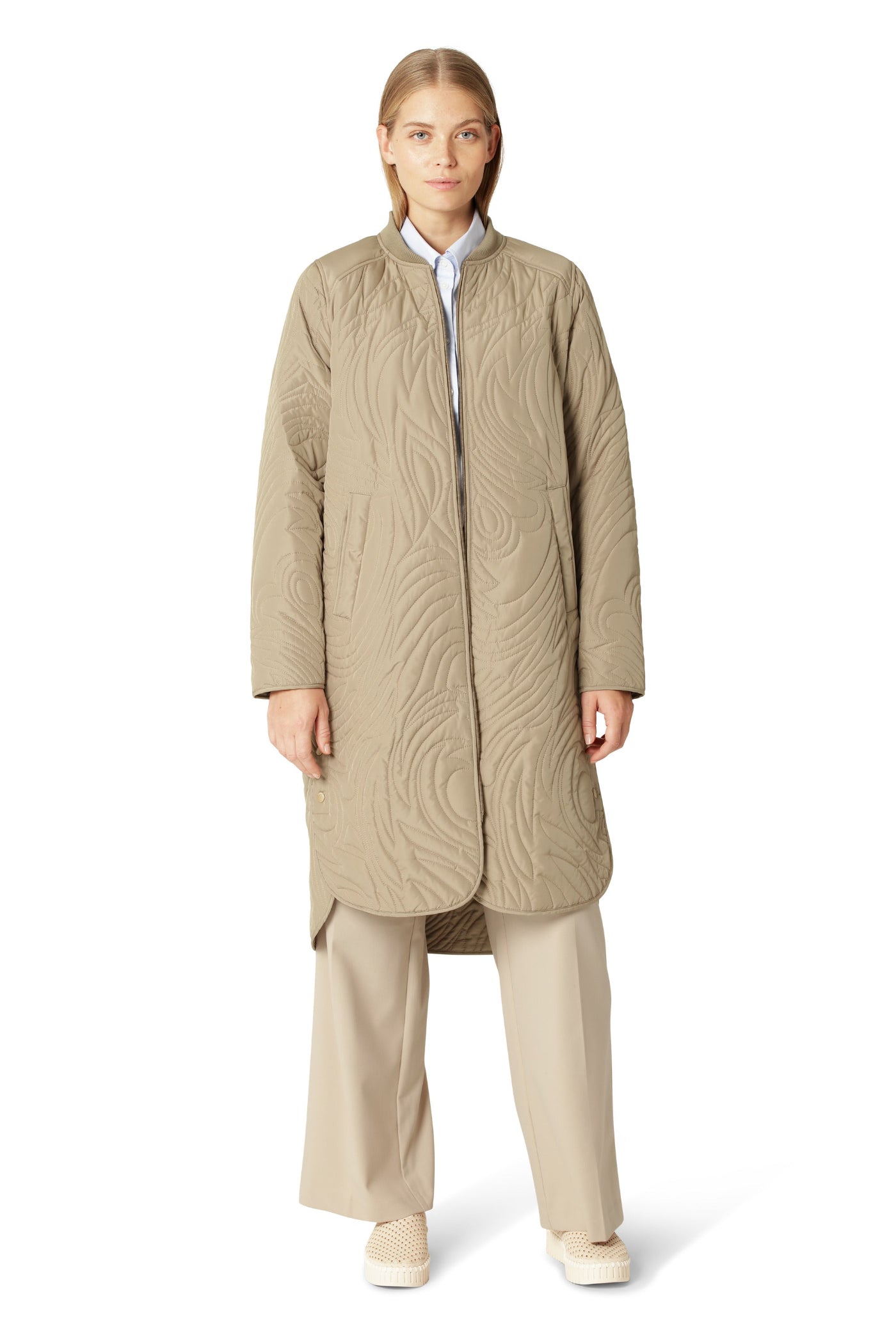 Woman wearing a beige quilted coat on a white background