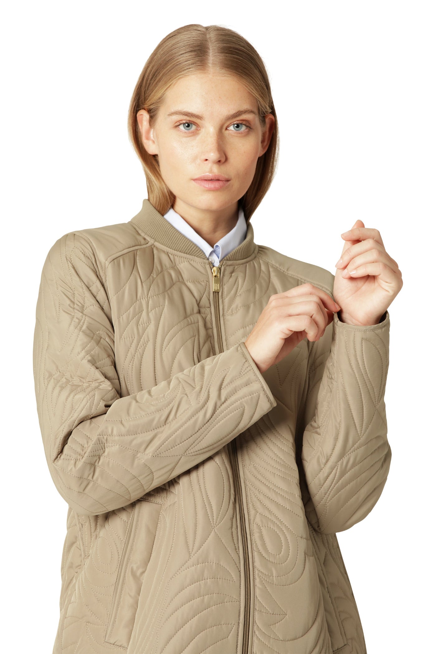 Woman wearing a beige quilted jacket on a white background