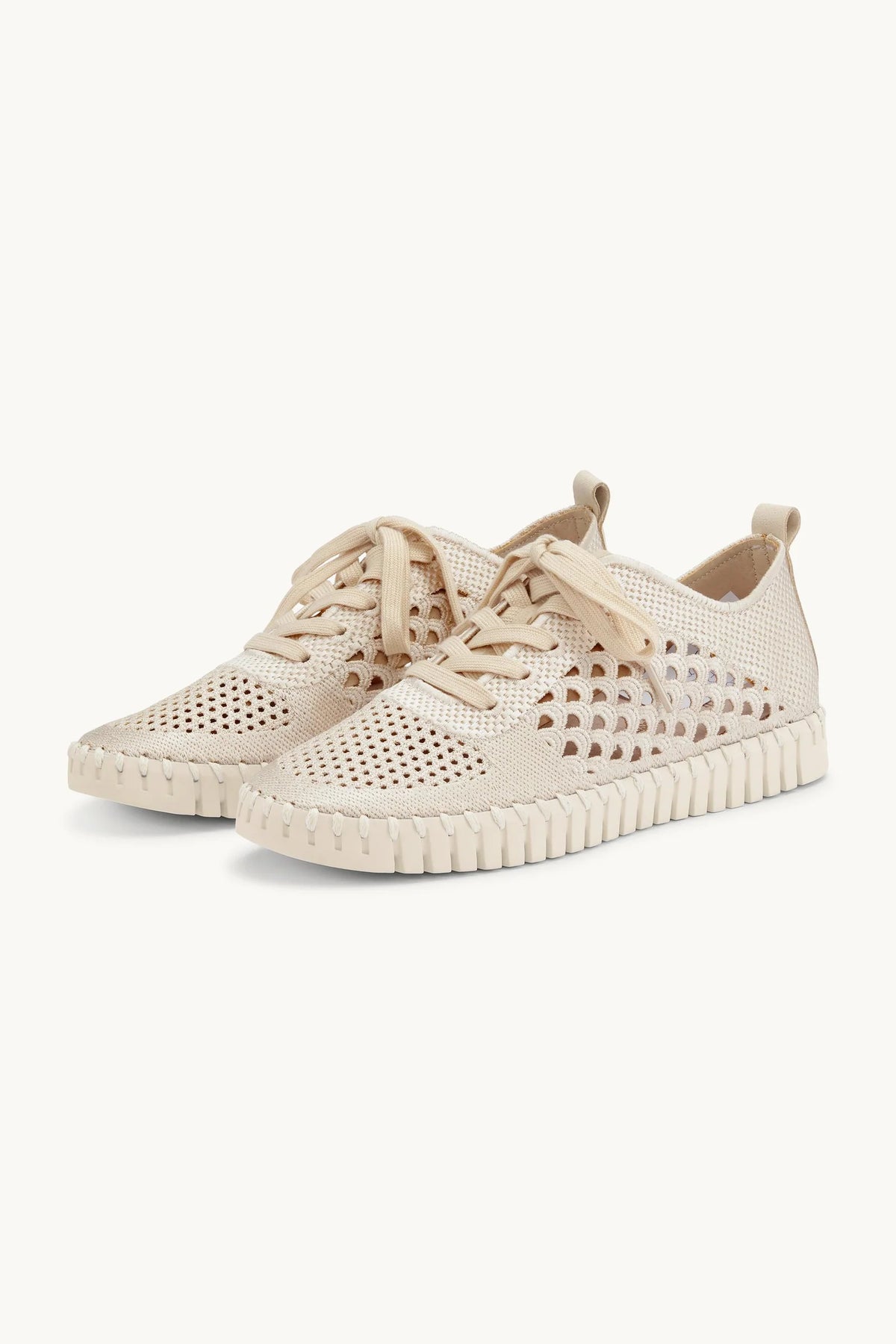 Beige sneakers with perforated design on a white background