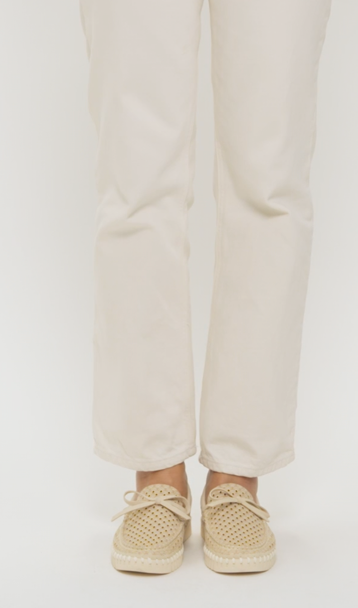 A person wearing off-white straight-leg pants and beige woven espadrille loafers, shown from the knees down against a plain light background.