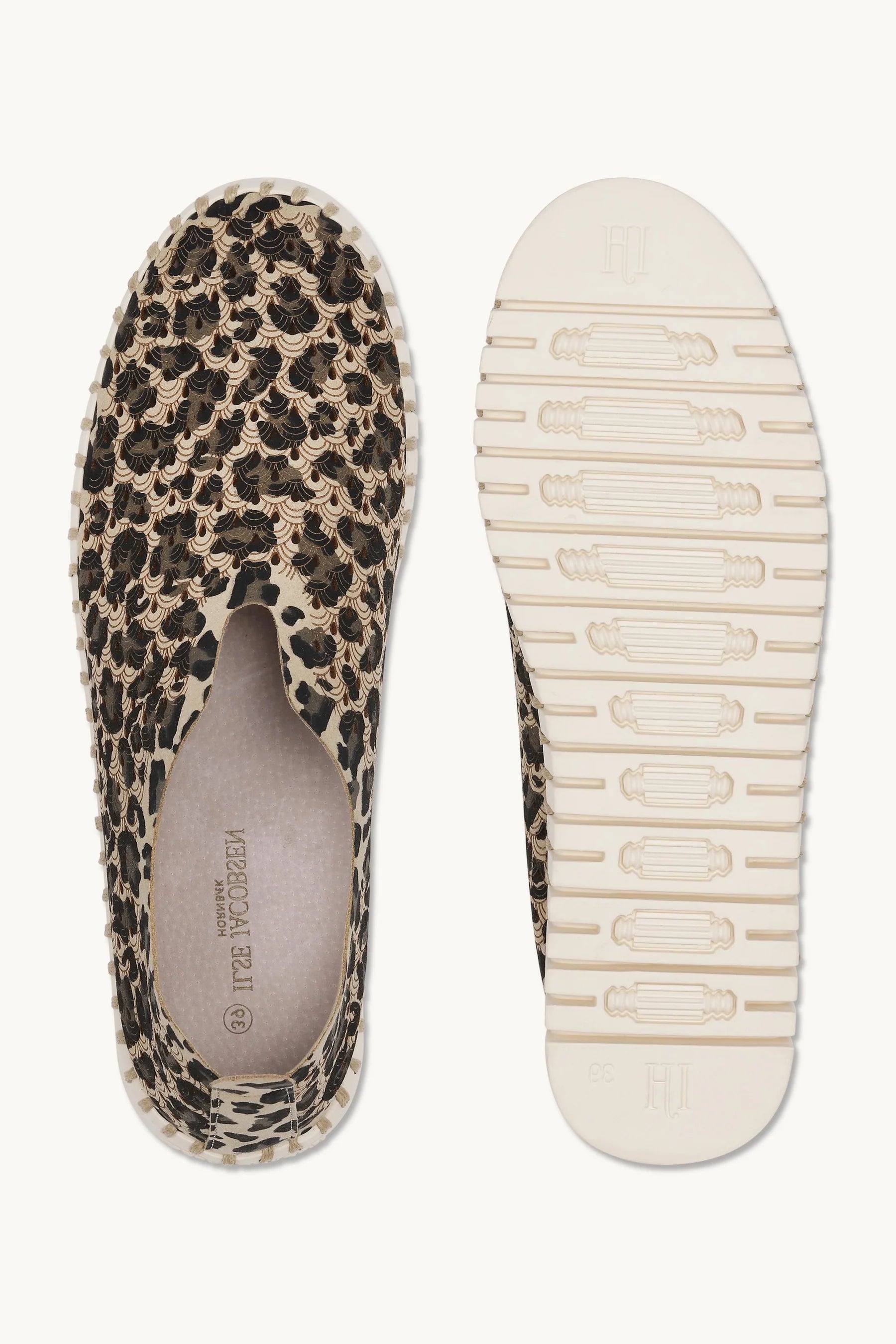 Pair of leopard print flat shoes with white rubber sole on a plain background. 