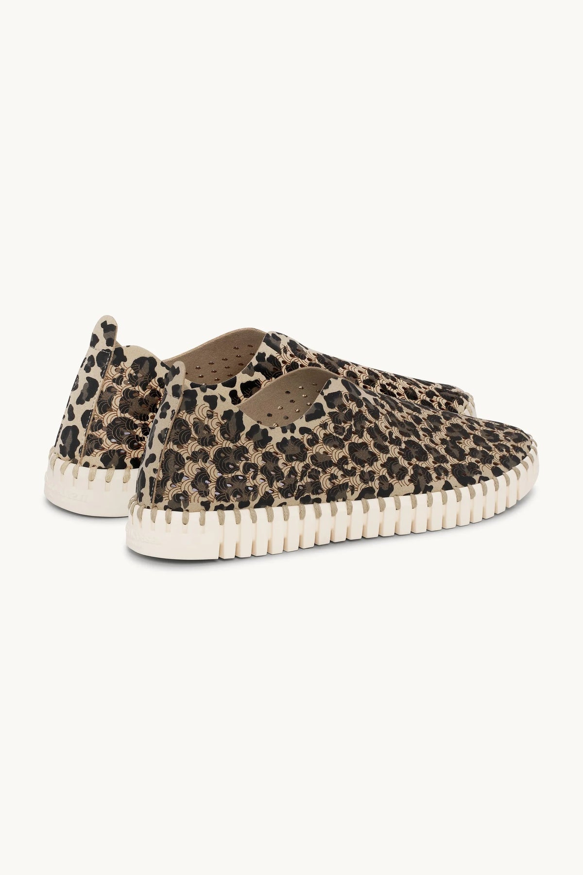 Pair of leopard print flat shoes with white rubber sole on a plain background. 