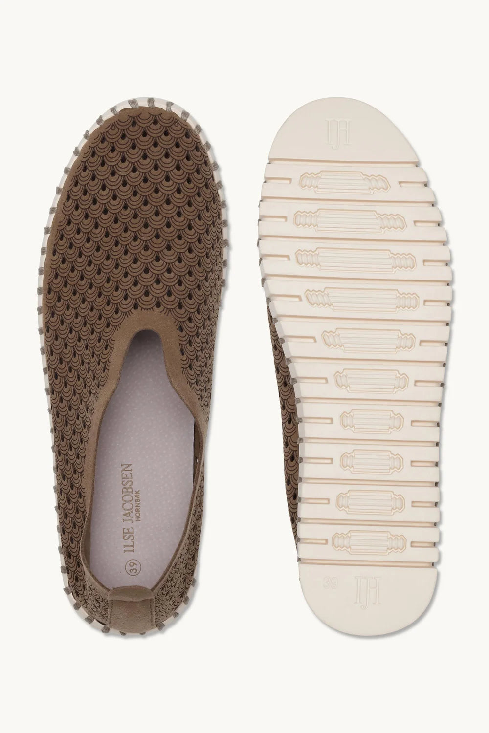 Pair of brown slip on shoes with lazer cut patter and white rubber soles on a plain background. 
