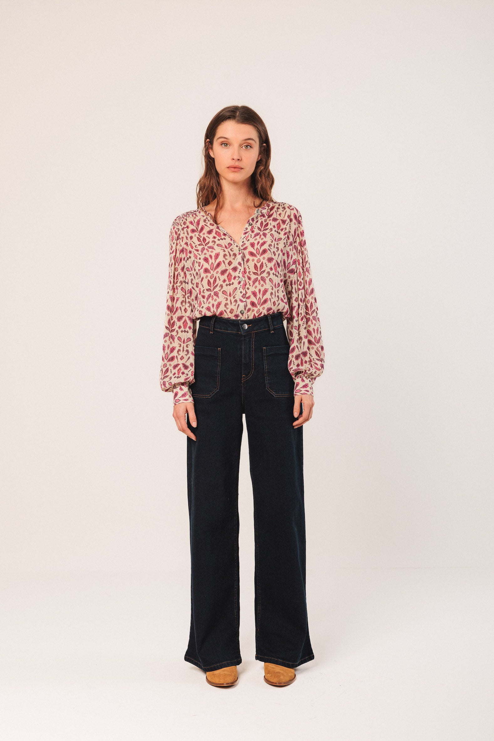 Woman wearing a floral blouse and black pants on a white background