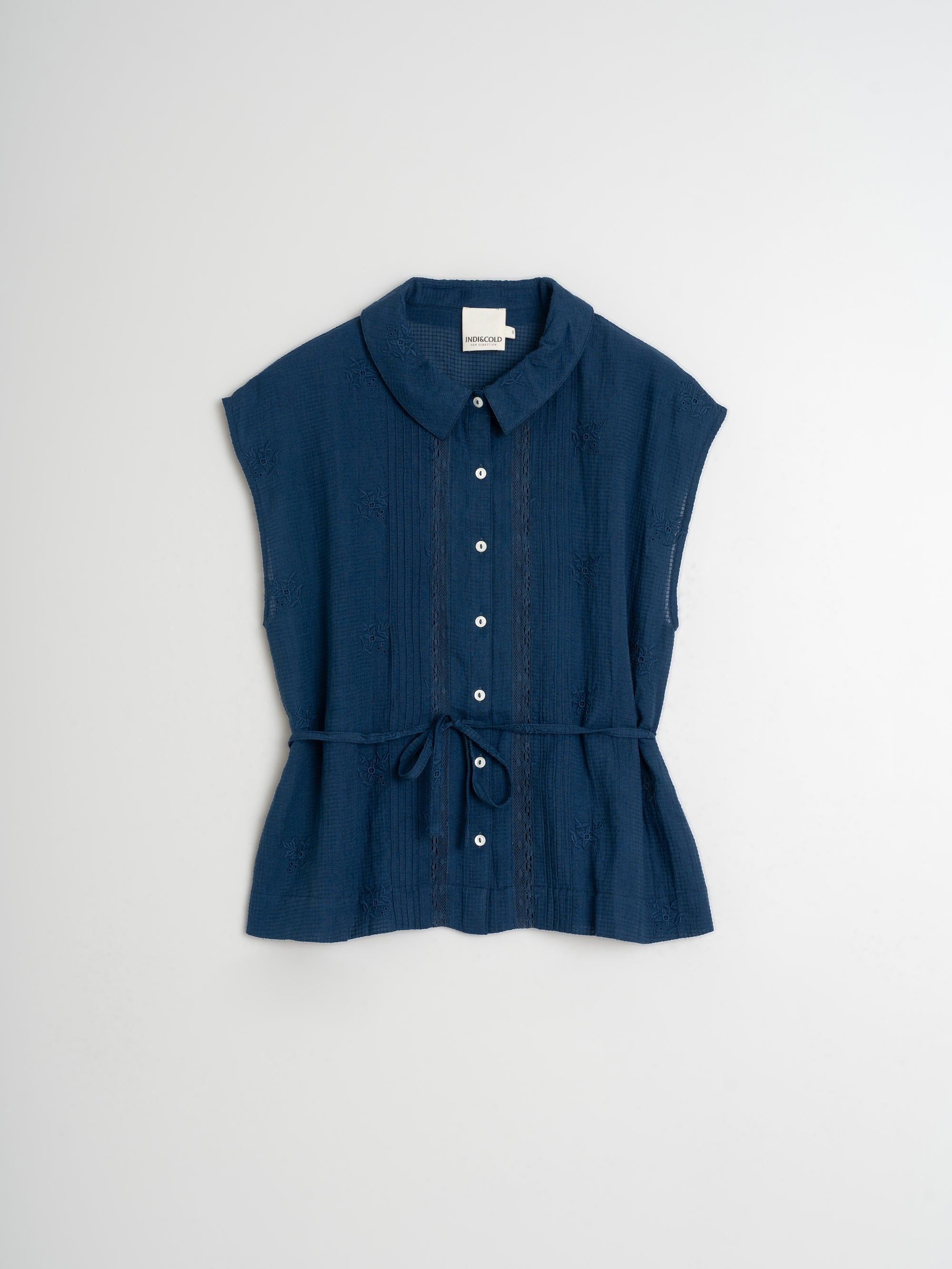 Blue sleeveless blouse with a belt on a light gray background