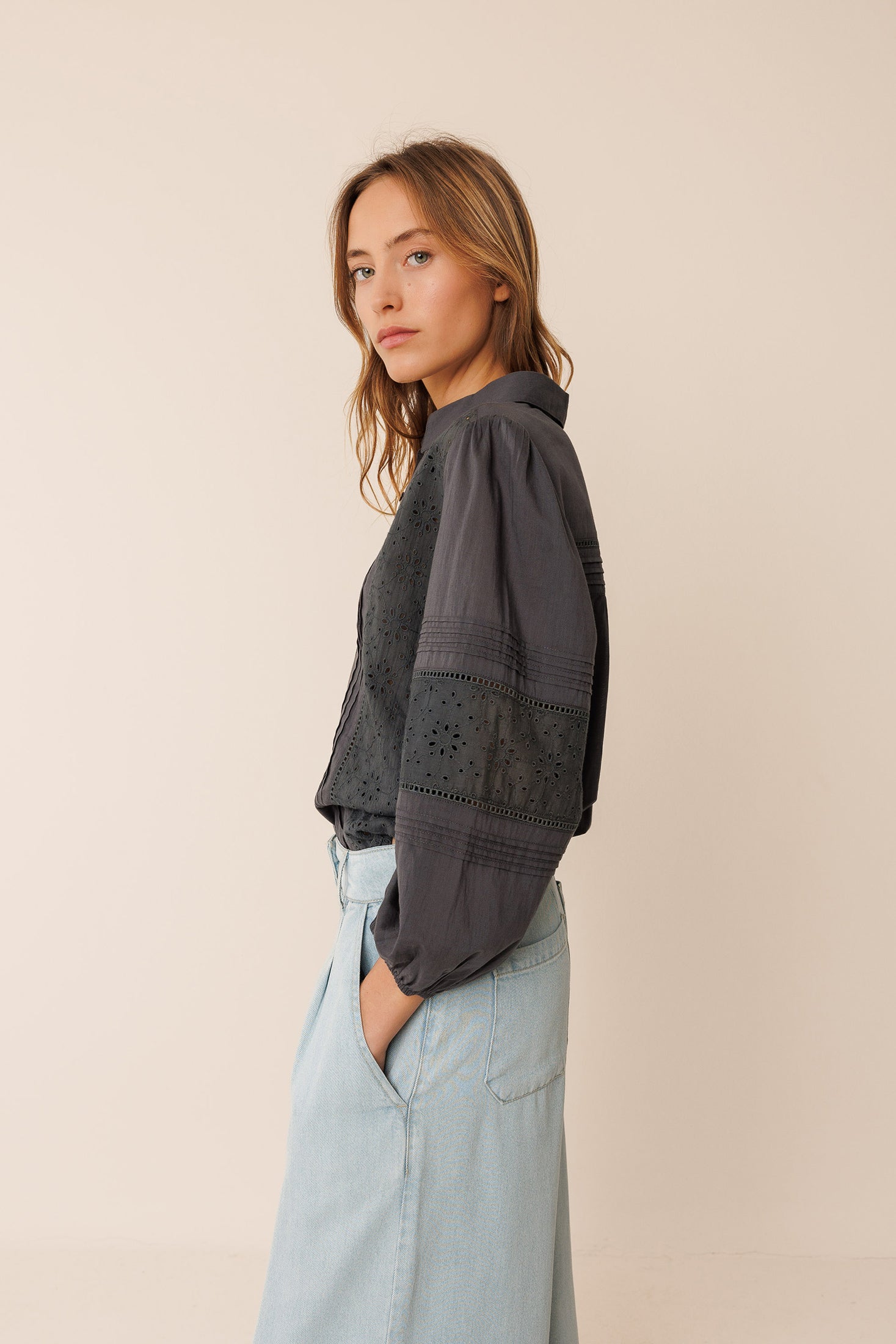 Woman wearing a black shirt and light blue pants on a beige background