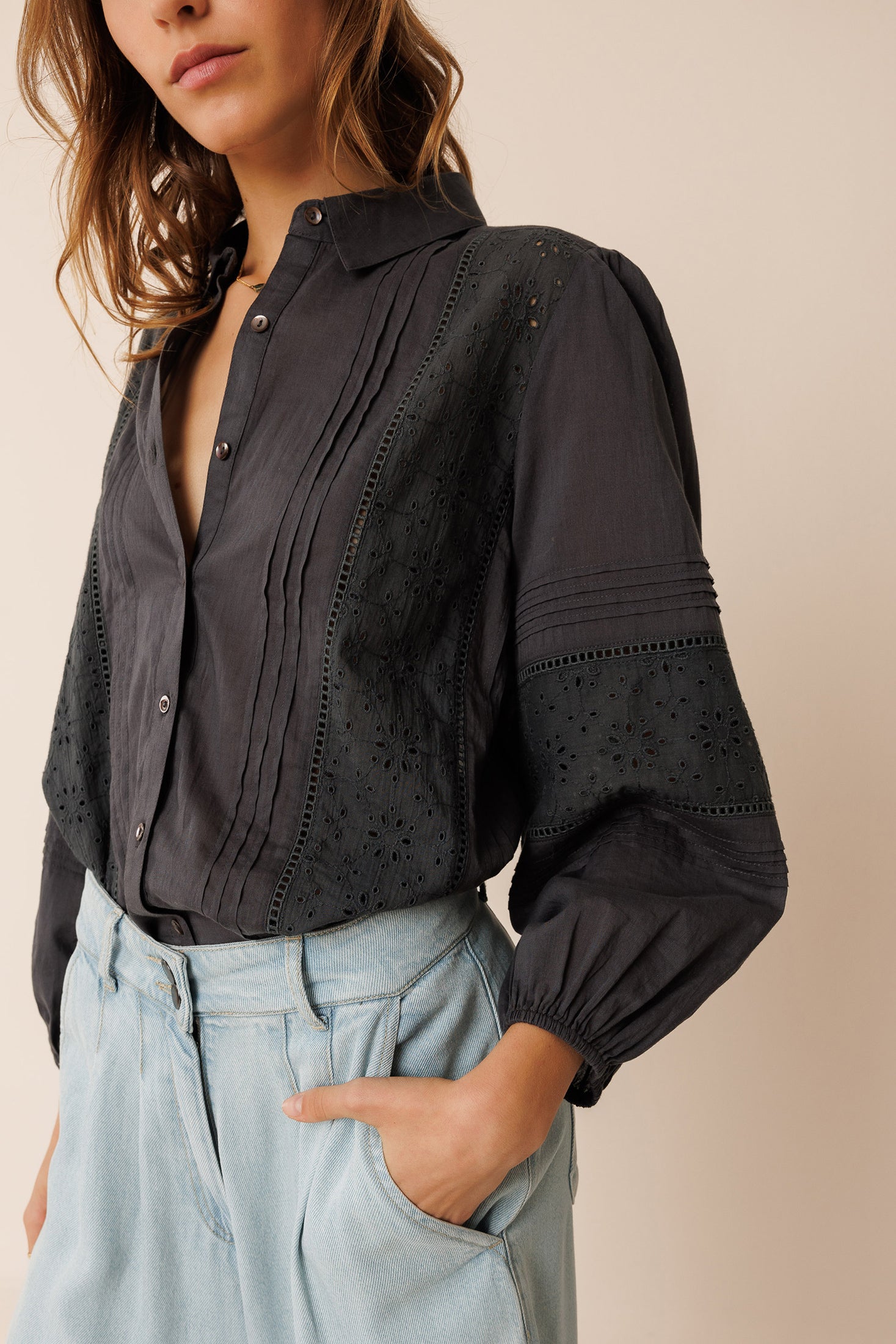 Woman wearing a black shirt and light blue pants on a beige background
