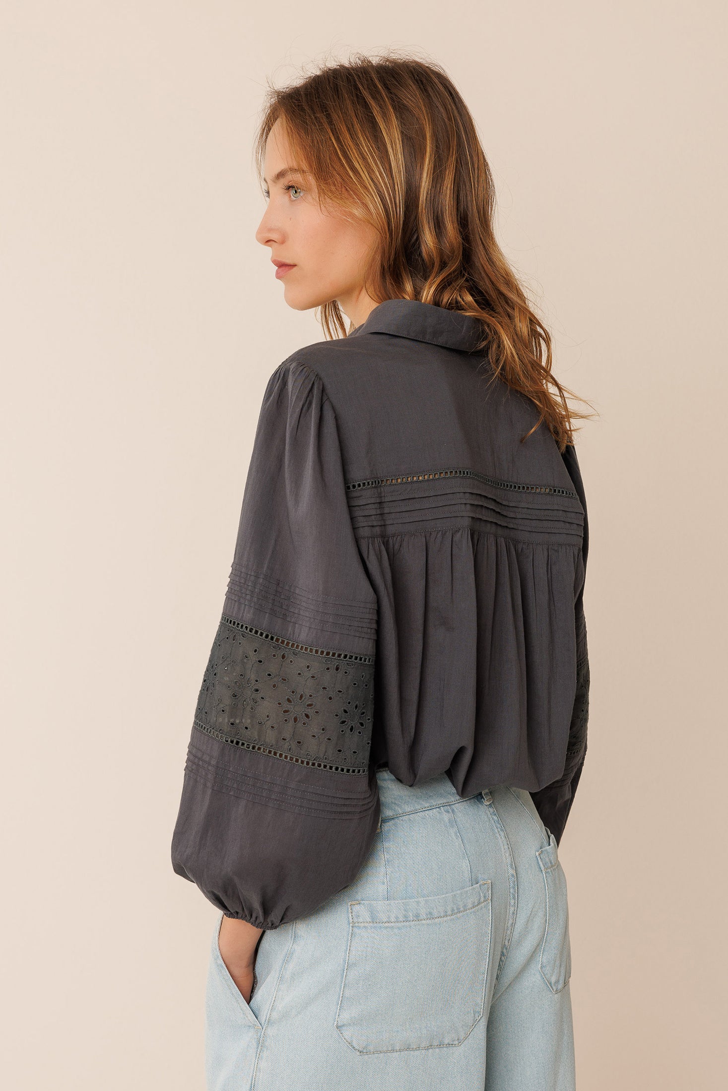 Woman wearing a black shirt and light blue pants on a beige background