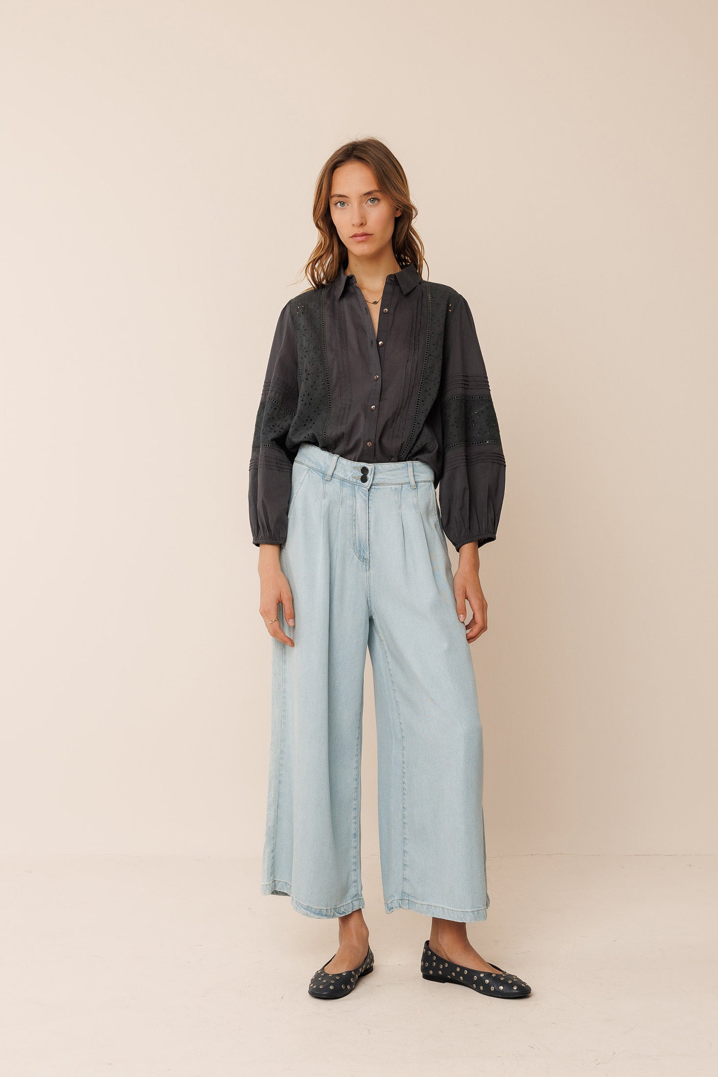 Woman wearing a black shirt and light blue pants on a beige background