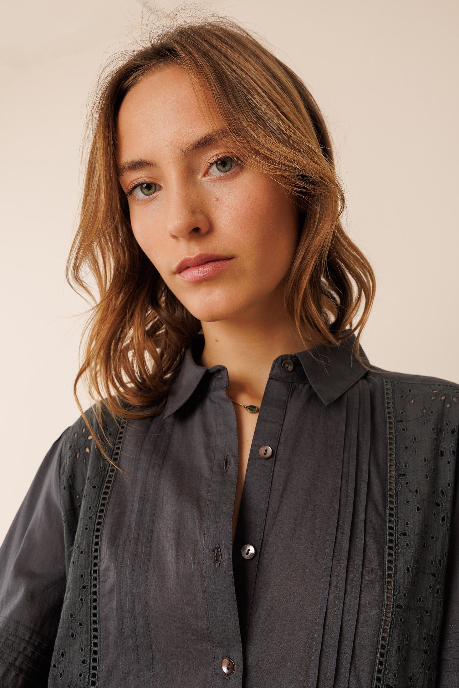 Woman wearing a dark gray blouse against a plain background