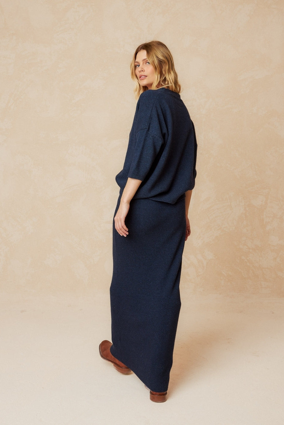 Navy short sleeve wool cardigan with front buttons, dropped shoulder and ribbed hem and cuffs.  Back view. 