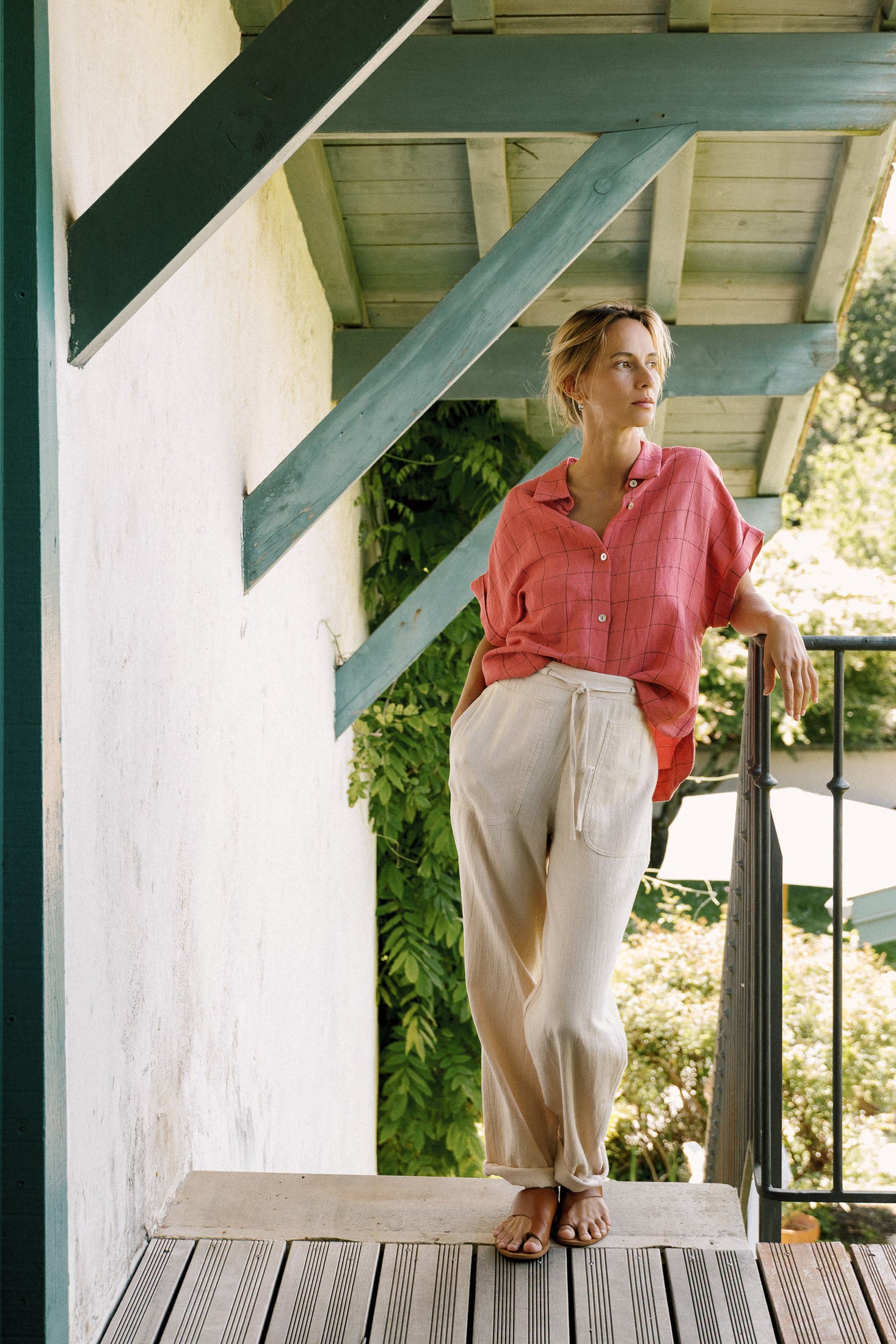 Woman standing on a wooden deck with greenery in the background